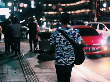 Rear view of people walking on illuminated street at night