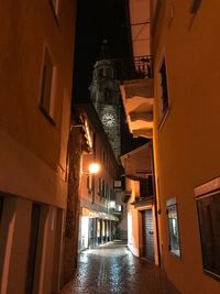 Empty alley amidst buildings in city at night