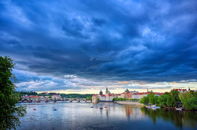 Buildings by river against sky in city