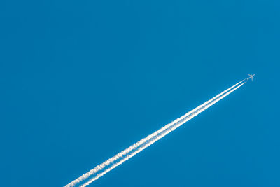 Low angle view of vapor trail against blue sky