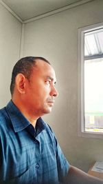 Portrait of man looking through window at home