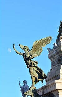 Low angle view of angel statue against blue sky