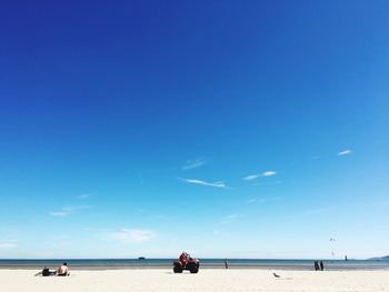 People at beach against blue sky