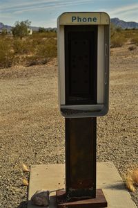 Close-up of telephone booth on field against sky