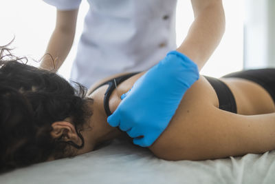 Crop unrecognizable therapist sticking needle on shoulder of female patient during alternative acupuncture procedure in professional rehabilitation salon