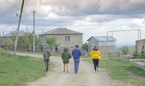 Rear view of men walking on field against sky