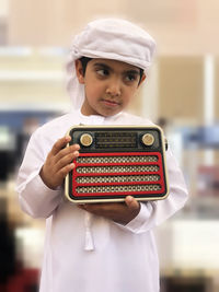 Boy holding vintage radio while standing at home