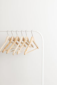 Wooden hangers on the white modern open rack. pale neutral colours , consumerism concept.