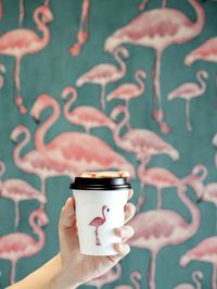 Close-up of hand holding coffee cup against sky