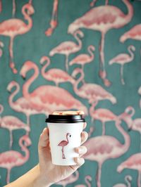 Close-up of hand holding coffee cup against sky