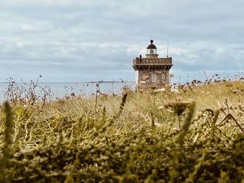 Lighthouse by sea against sky