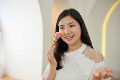 Portrait of young woman applying lipstick