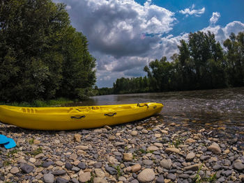 Yellow boat moored by lake against sky