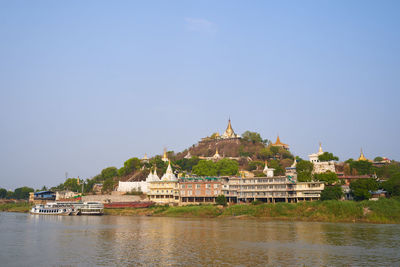 Built structure by river against building against clear sky