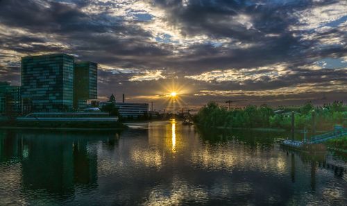 River by buildings against sky during sunset