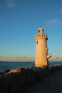 Lighthouse by sea against clear sky