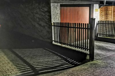 Shadow of railing on footpath against building