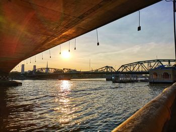 Bridge over river against sky during sunset