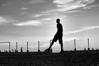 Silhouette boy holding ball under foot