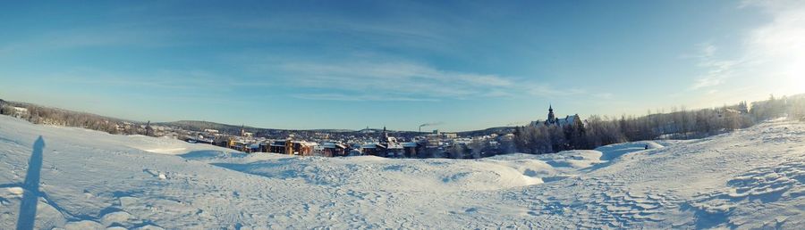 Panoramic shot of snow covered landscape against sky