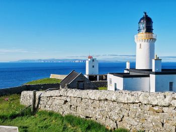 Lighthouse by sea against sky