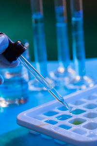 Close-up of hand holding glass against blue background