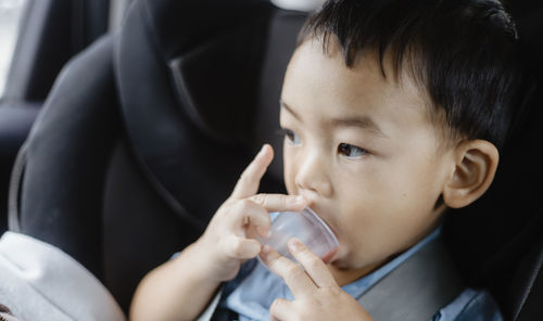 Close-up portrait of cute boy drinking water