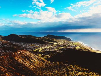 Aerial view of sea by mountain against sky