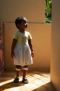 Full length of girl standing by wall outdoors