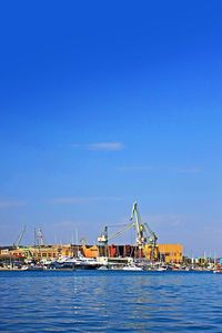 Cranes at harbor against clear blue sky