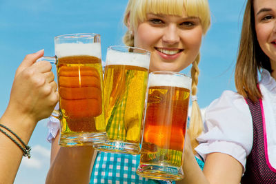 Portrait of smiling young woman toasting beer glasses with friends