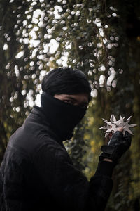 Portrait of man standing by tree during winter