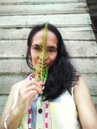 Portrait of young woman holding plant