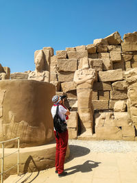 Tourist among ancient ruins. one man on excursion to karnak temple photographs sights. luxor, egypt