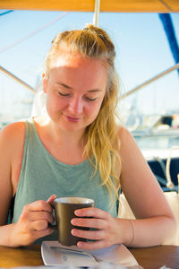 Close-up of young woman drinking coffee while sitting indoors