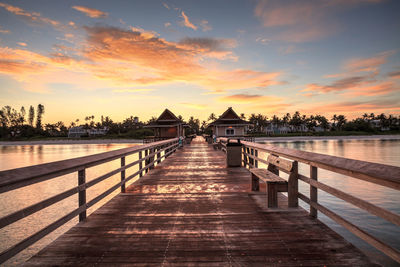 Pier amidst buildings against sky during sunset