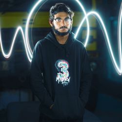 Portrait of young man standing against illuminated light