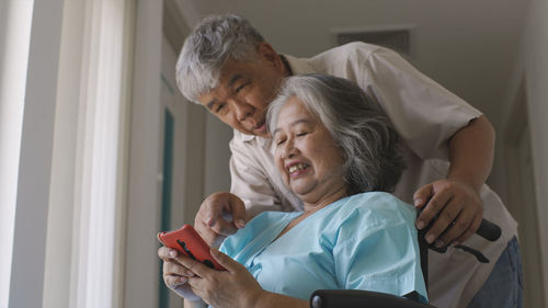 A senior woman and her husband making a video call on a mobile phone in the hospital