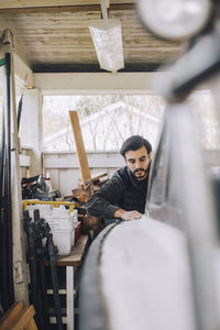 Mid adult man cleaning nautical vessel in garage