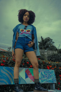 Portrait of young woman standing against sky