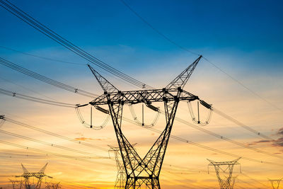 Low angle view of silhouette electricity pylon against romantic sky