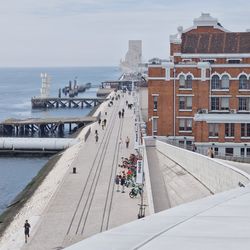 Elevated view looking west over waterside promenade, with jetties.