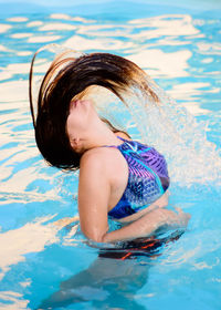 Girl splashing water in swimming in pool