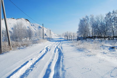 Snow covered landscape against blue sky