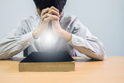 Midsection of man reading book on table