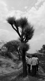 Rear view of couple standing on field against sky