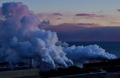 Panoramic view of factory against sky at sunset