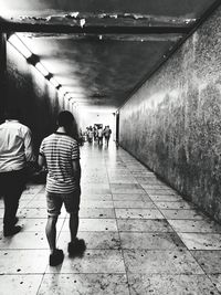 Rear view of people walking in illuminated tunnel