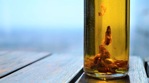 Close up view on bottle of gold olive oil with red paprika at wooden surface