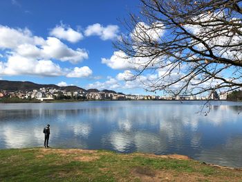 Man standing by lake against cloudy sky